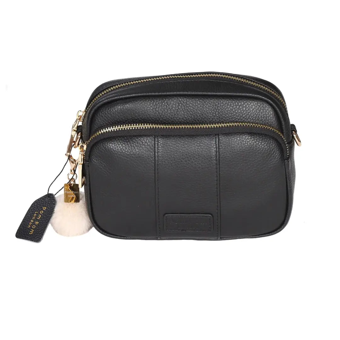 black crossbody bag with a cream pom pom and tag with pom pom london