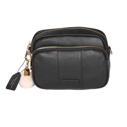 black crossbody bag with a cream pom pom and tag with pom pom london