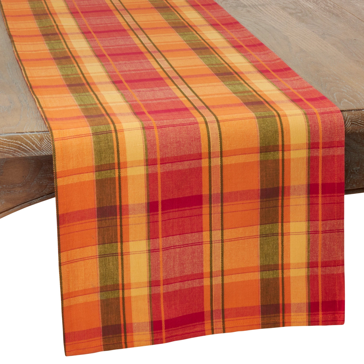 A plaid table runner with vertical stripes in orange, red, yellow, and olive green, draped over a wooden table.