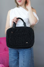 Women holding a black leopard print Stia Totally Toiletry Hanging Bag