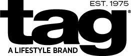 The black and white logo for 'tag', featuring the wordmark 'tag' in a bold lowercase font, 'EST. 1975' at the top right, and 'A LIFESTYLE BRAND' at the bottom available at The Little Exchange Fine Gifts in Oakwood, just south of Dayton Ohio