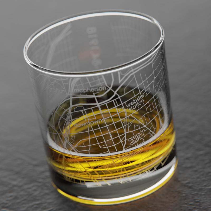 A clear rocks glass with an etched map of Dayton, OH, including latitude and longitude coordinates on the side.