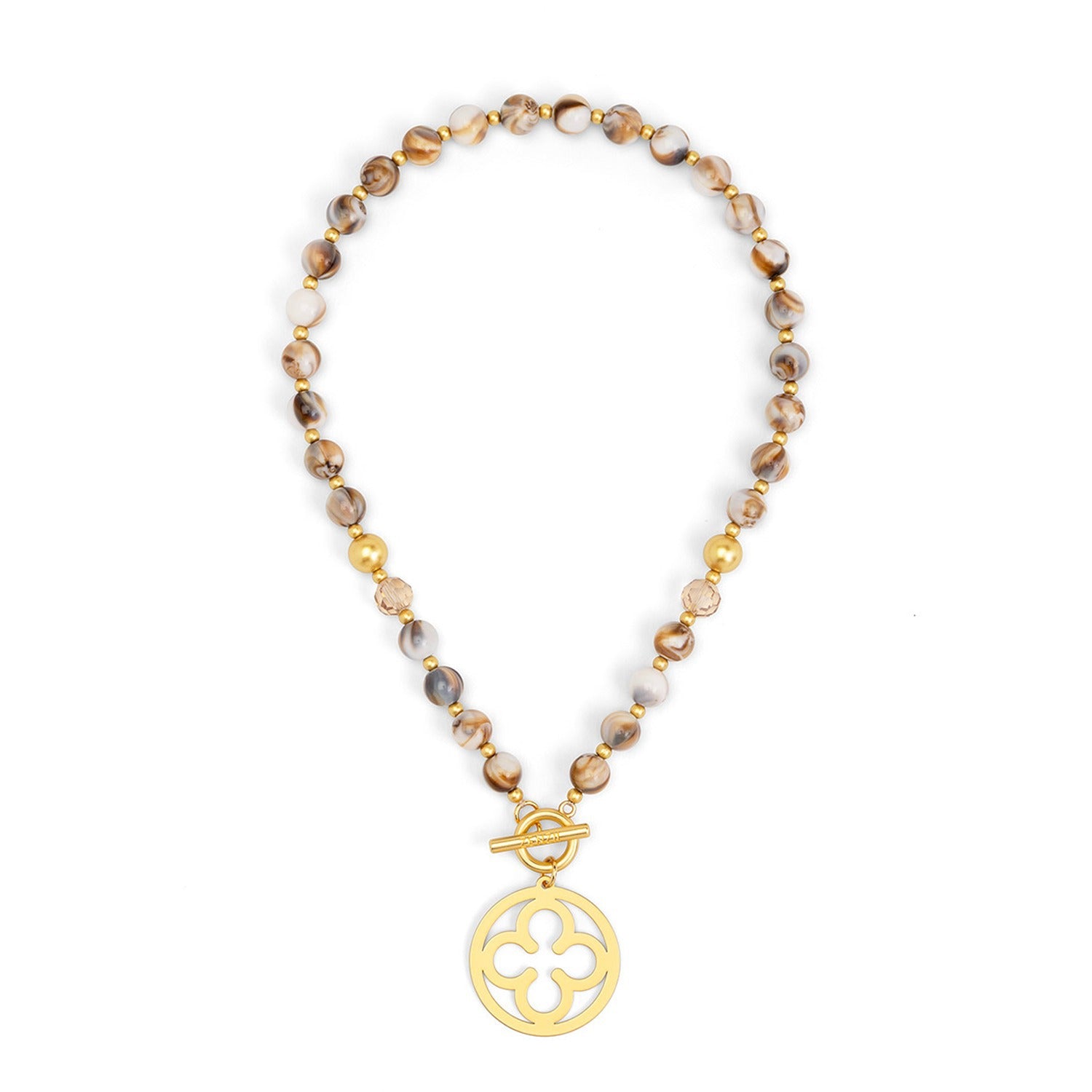 A beaded necklace featuring brown and beige marbled beads with small gold spacer beads, finished with a gold toggle clasp and a circular gold pendant with a quatrefoil cutout design.